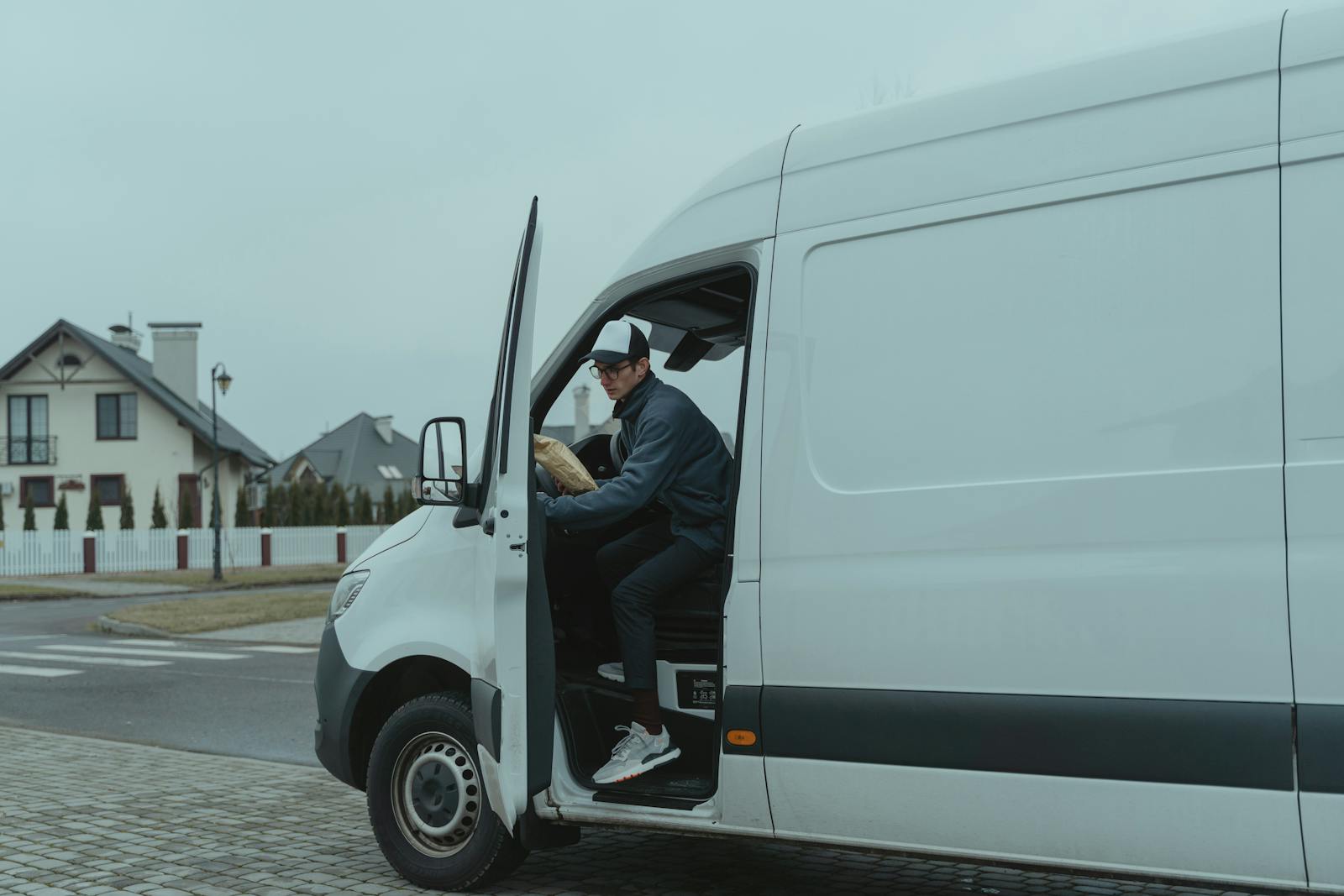 Courier stepping out of a delivery van in a suburban street