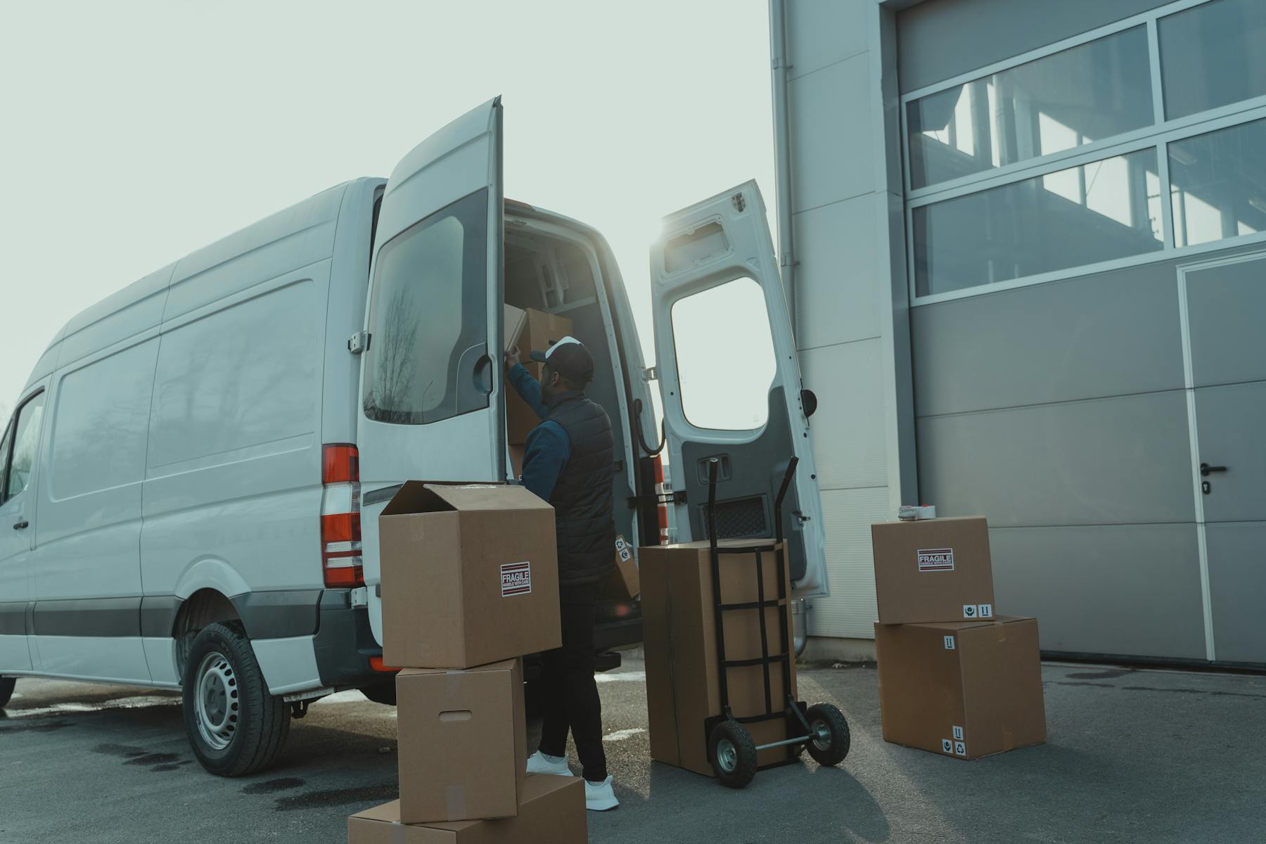 Delivery operator loading parcels into a white van at a distribution facility